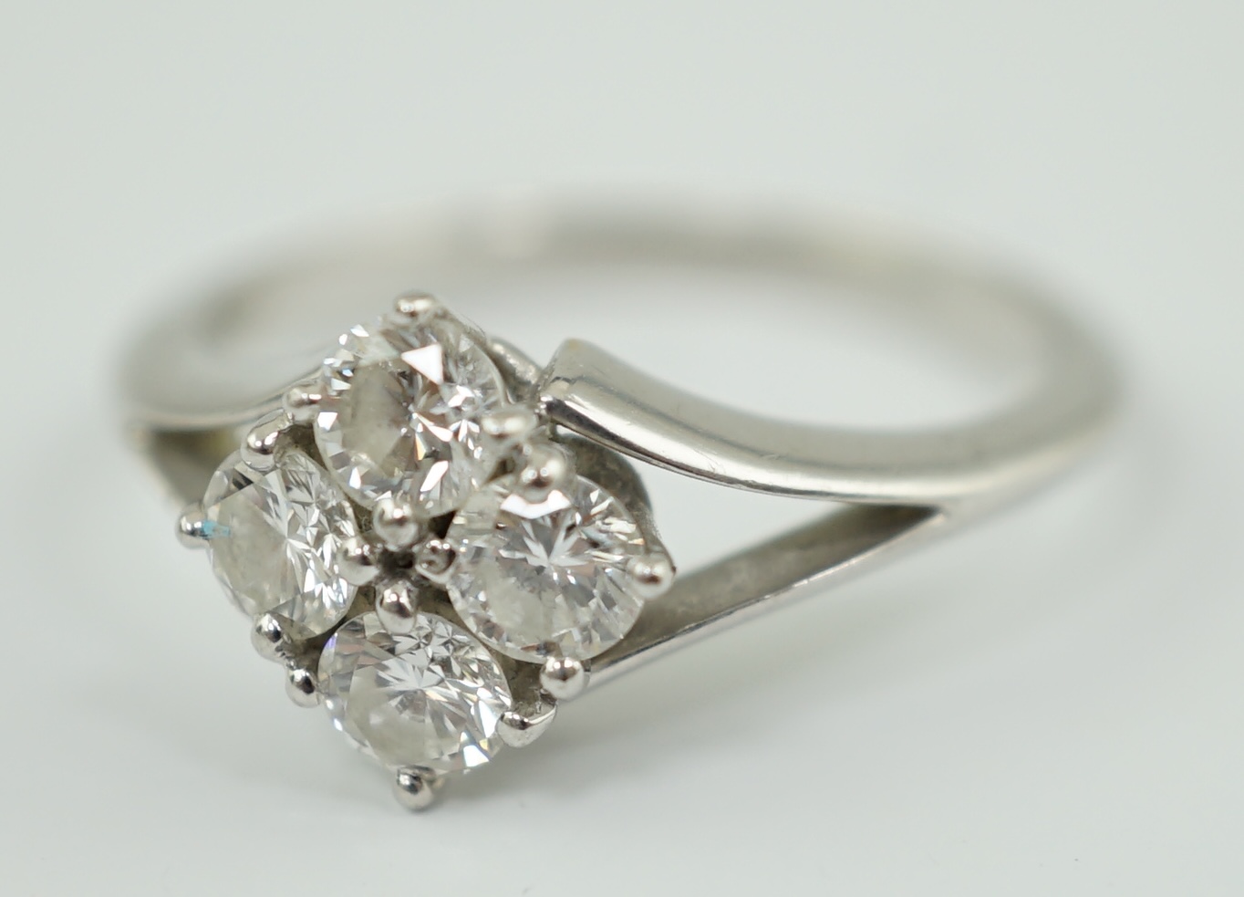 A modern platinum and four stone diamond cluster set ring